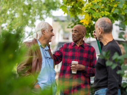 Group of senior men of various backgrounds having a friendly chat in a front yard.