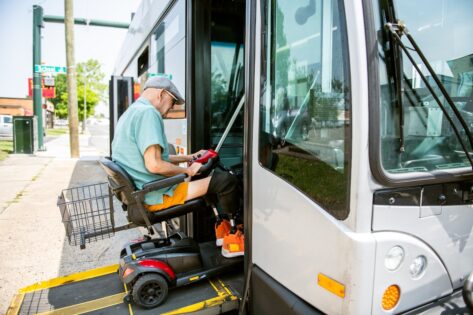 Disabled senior man accessing the bus on mobility scooter